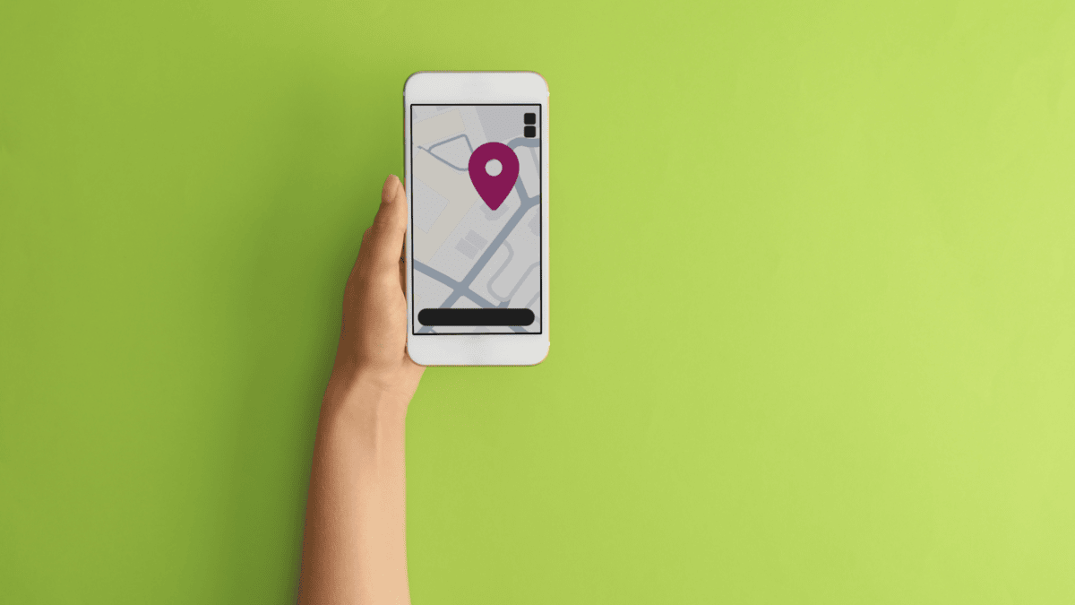 An arm extending into the screen holding an iPhone showing an illustration of a map